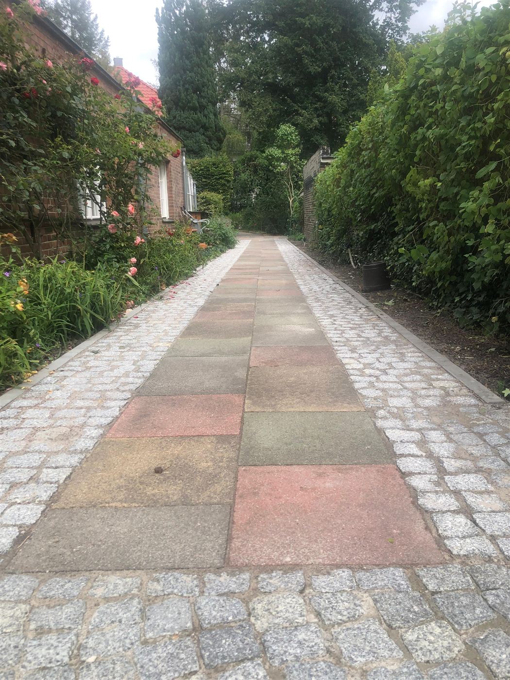 Erneuerte Grundstückszufahrt mit wiederverwendeten Bestandsplatten und Natursteinpflaster